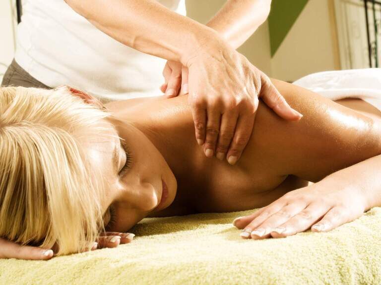 Eine Frau erhält eine Massageanwendung im Wellnessbereich des Hotels in Bodenmais